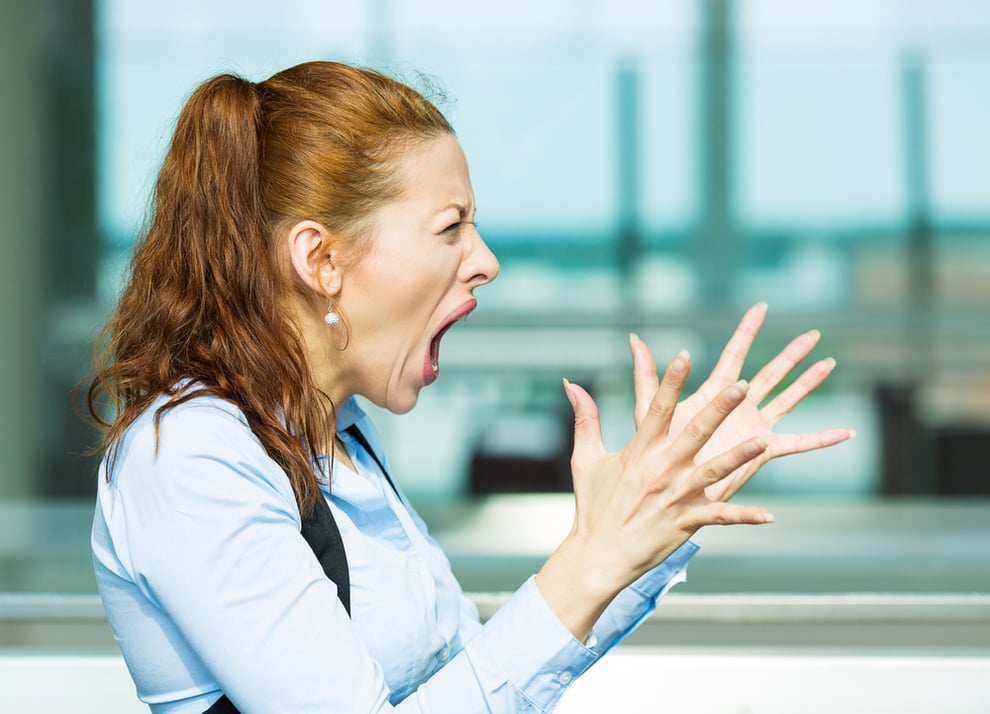 Closeup side view profile portrait mad angry upset hostile young businesswoman, worker, furious yelling hands in air, isolated background office windows. Negative emotions, facial expression, reaction