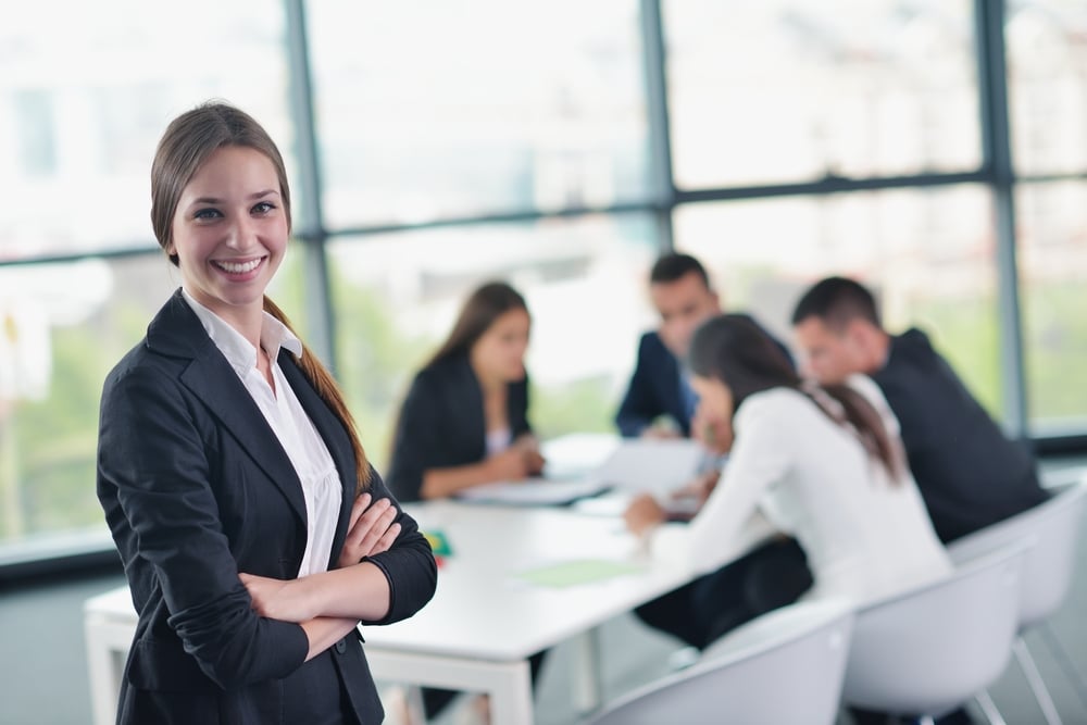 happy young business woman with her staff, people group in background at modern bright office indoors