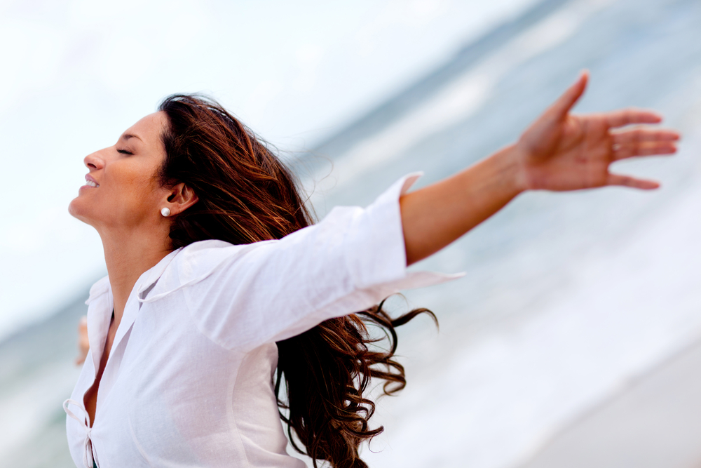 Woman relaxing at the beach with arms open enjoying her freedom